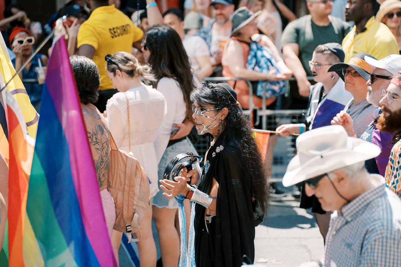 Participants at a pride parade, showcasing diversity and celebration with rainbow flags and colorful attire.