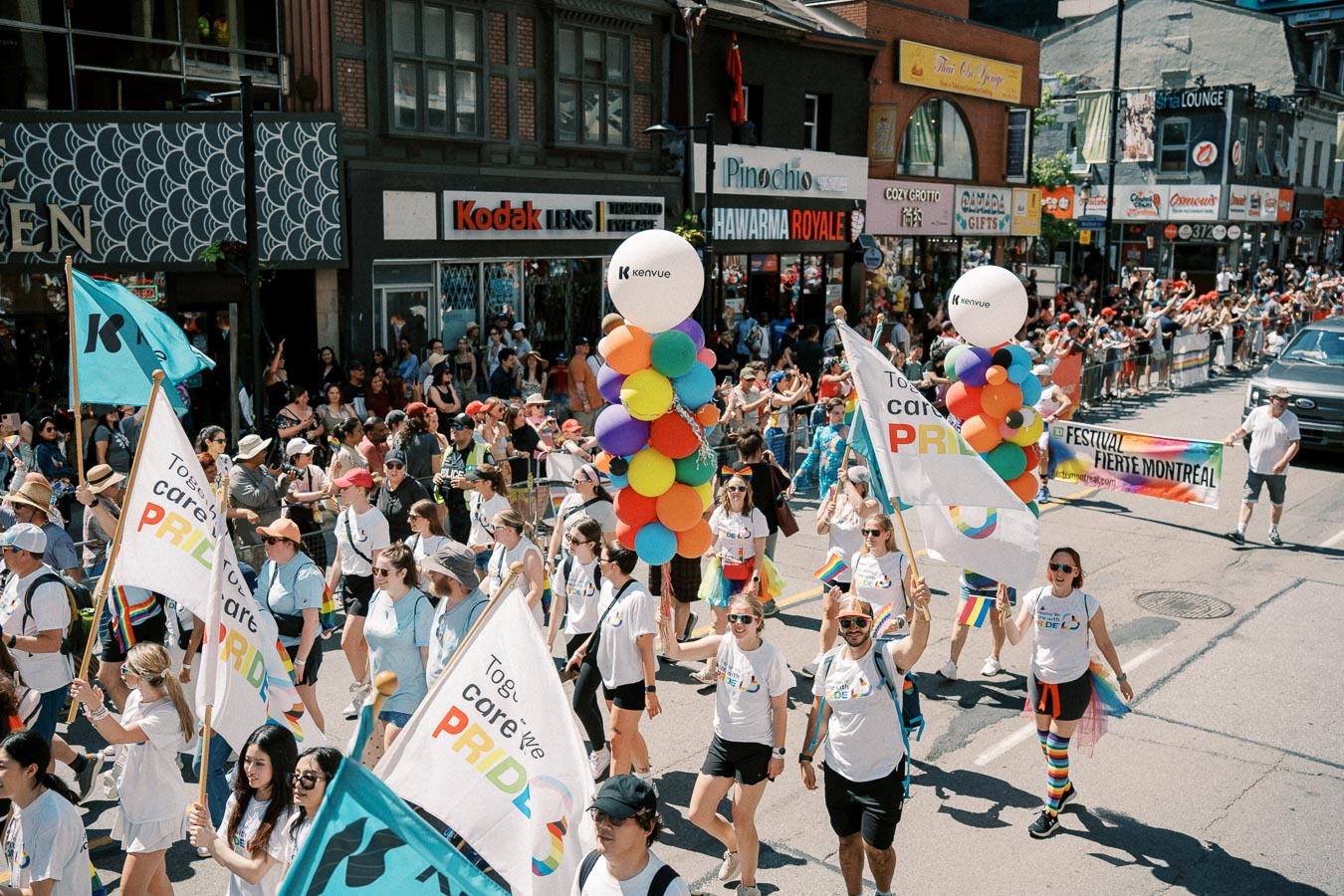 Participants march in the Montreal Pride Parade, carrying rainbow flags and balloons, celebrating diversity and inclusion.