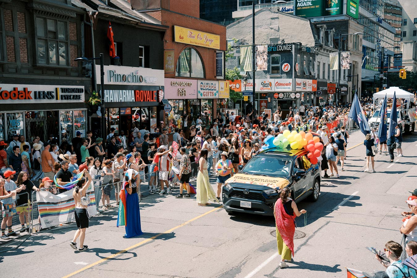 A vibrant parade with rainbow balloons and flags, celebrating diversity and inclusion on a bustling city street.