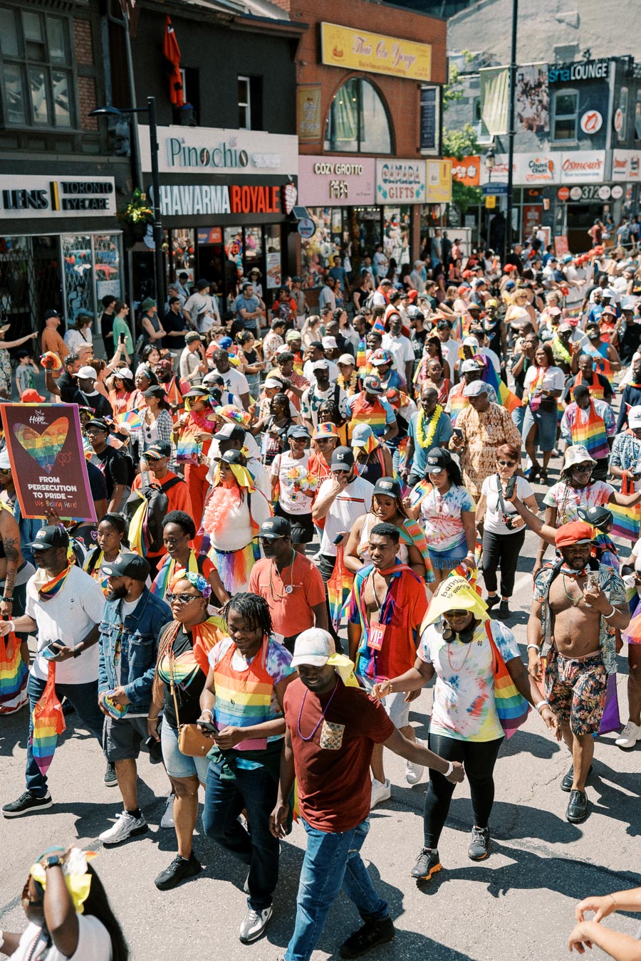 Participants in a vibrant pride parade march down a bustling street, adorned in rainbow colors and celebrating diversity.