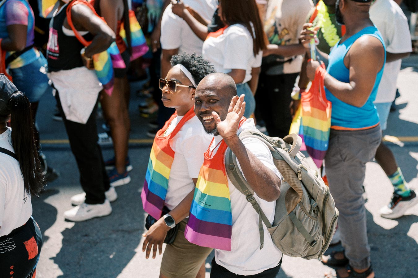 Participants at a pride parade wearing rainbow flags and vibrant attire, celebrating diversity and inclusion.