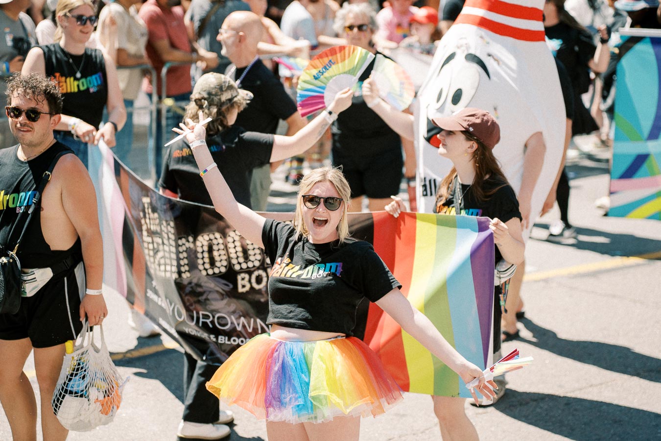 Participants joyfully celebrate at a pride parade, showcasing vibrant rainbow attire and accessories.