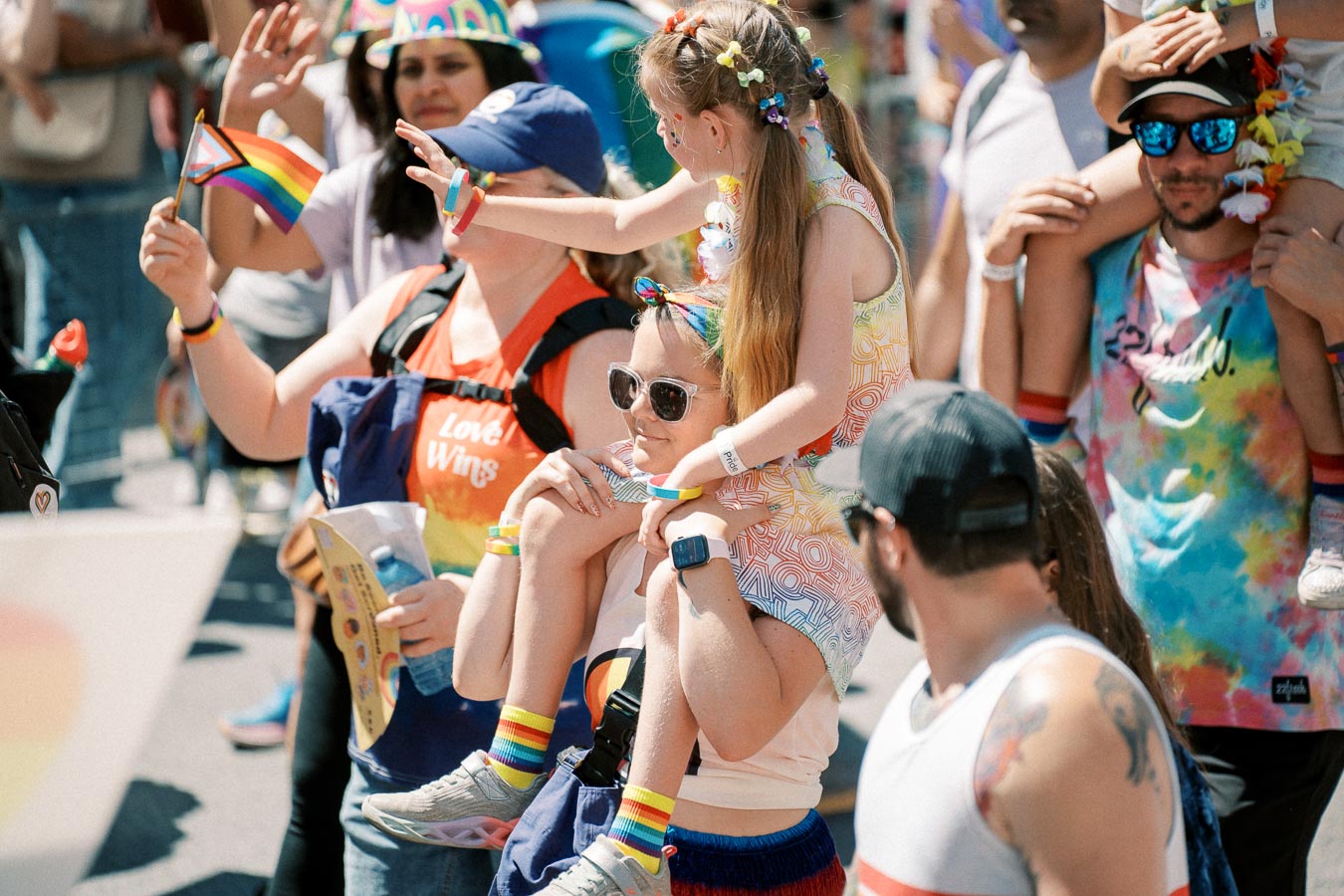 Participants at a pride parade celebrate with colorful attire and rainbow flags, embodying a spirit of inclusivity and joy.