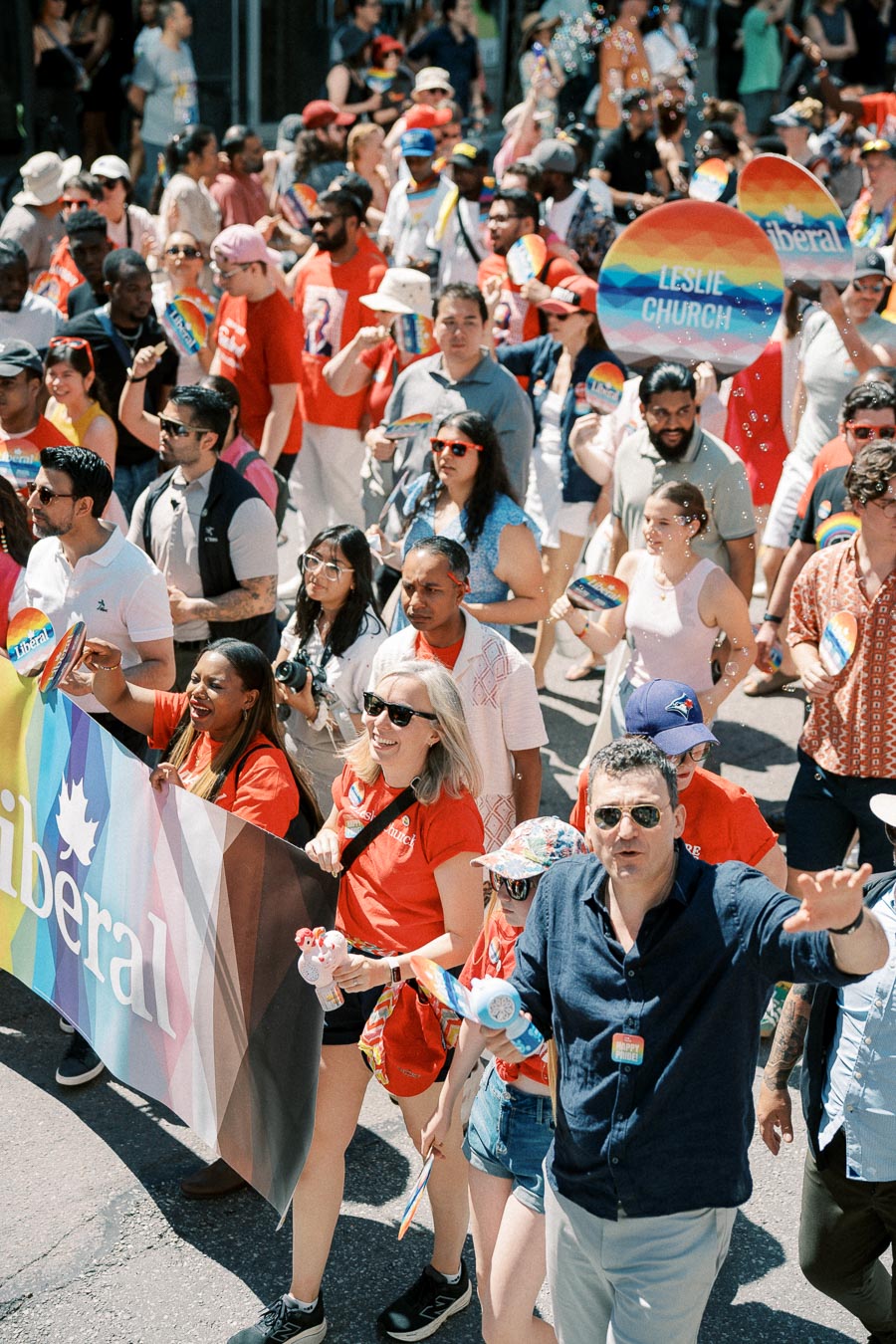 Participants in a parade celebrating diversity and inclusion, holding rainbow-themed signs and banners.