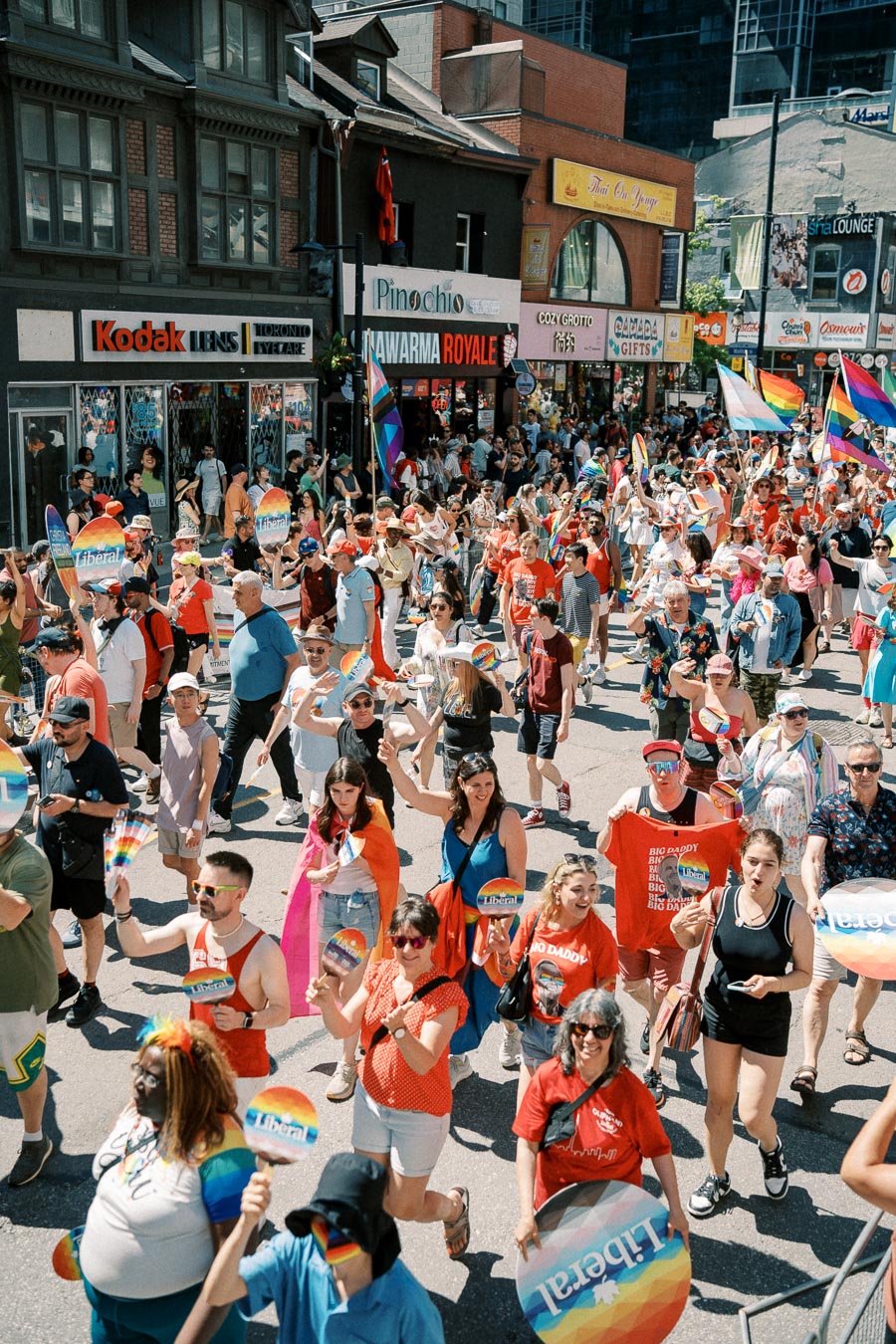 A lively parade celebrating diversity and pride, with participants holding rainbow flags and signs on a bustling city street.