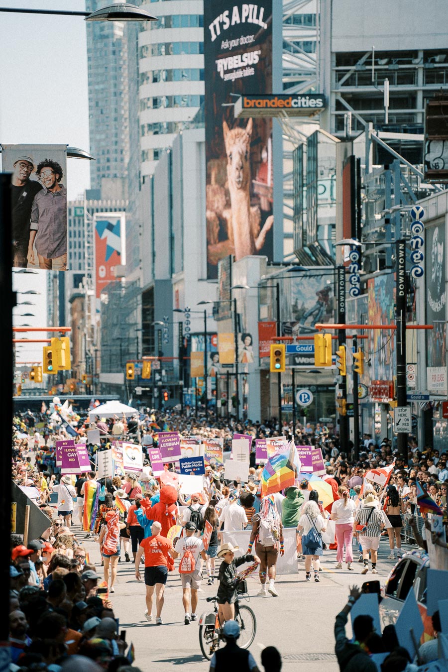 A lively parade takes place on a bustling city street, with participants carrying colorful signs and flags, celebrating diversity and inclusion.