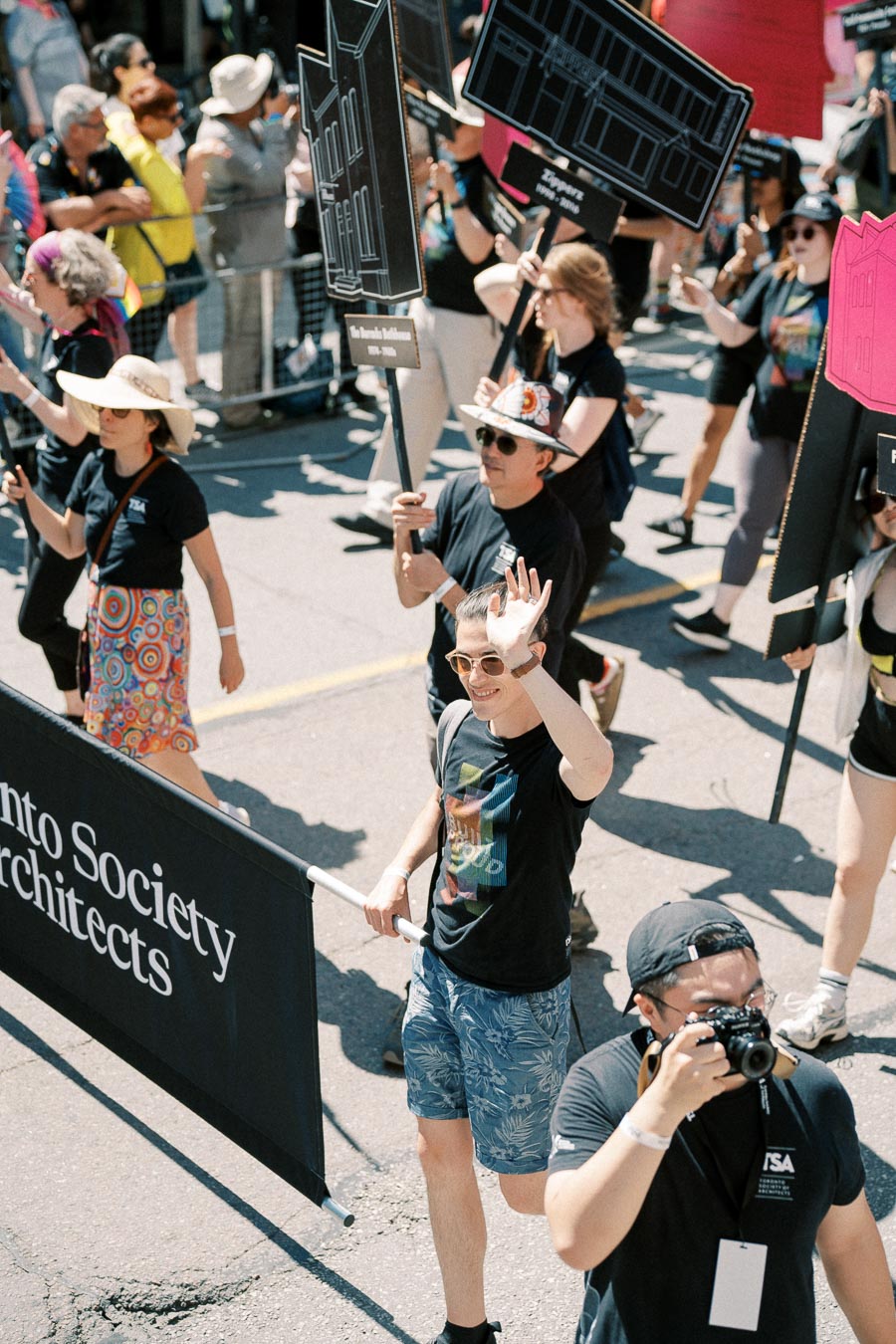 Participants from the Toronto Society of Architects march in a parade, holding signs and a banner.