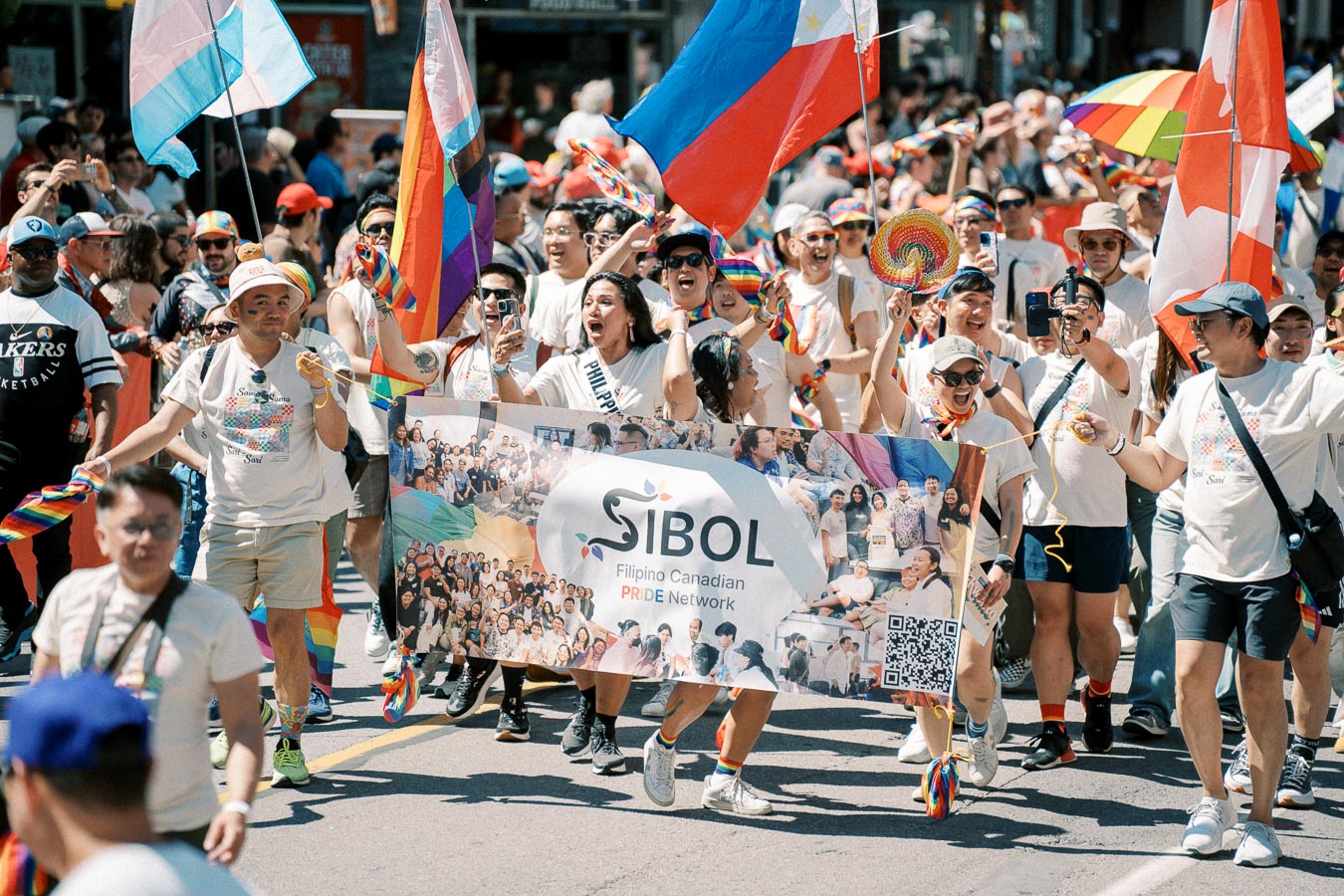 Participants in a pride parade march with the Sibol Filipino Canadian Pride Network banner, celebrating diversity and inclusion.