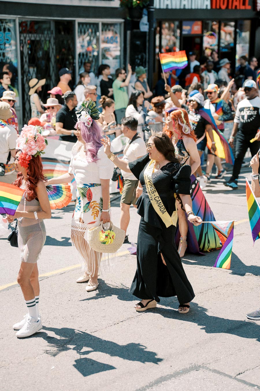 Participants in a colorful parade celebrating diversity and inclusion, holding rainbow flags and wearing vibrant outfits.
