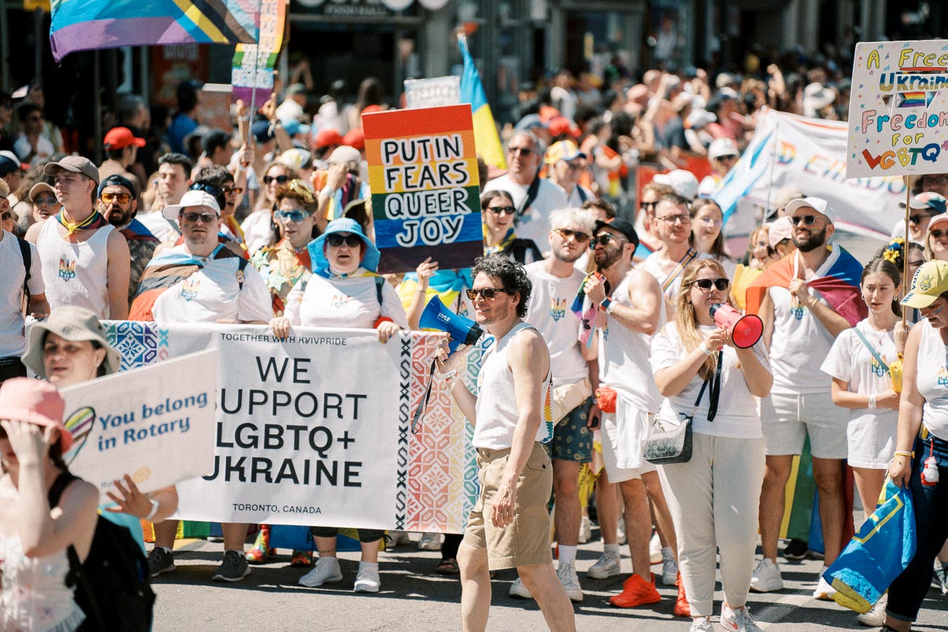 Participants in a pride parade show support for LGBTQ+ rights in Ukraine, holding signs and flags.