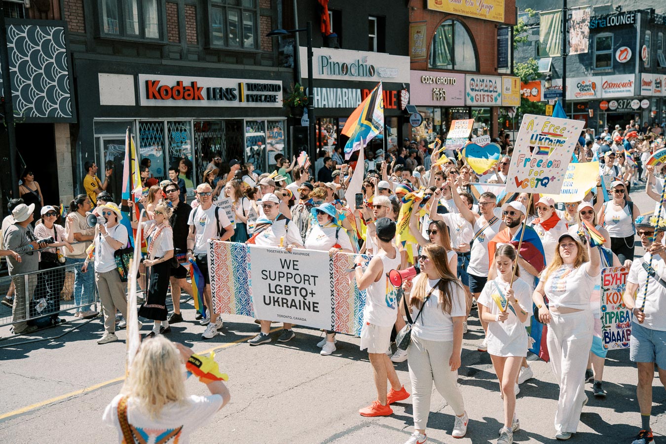Participants in a pride parade march in support of LGBTQ+ rights in Ukraine, carrying colorful signs and flags.
