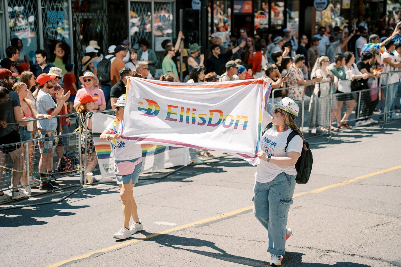 Participants in a parade hold an 'EllisDon' banner with rainbow colors, celebrating diversity and inclusion.