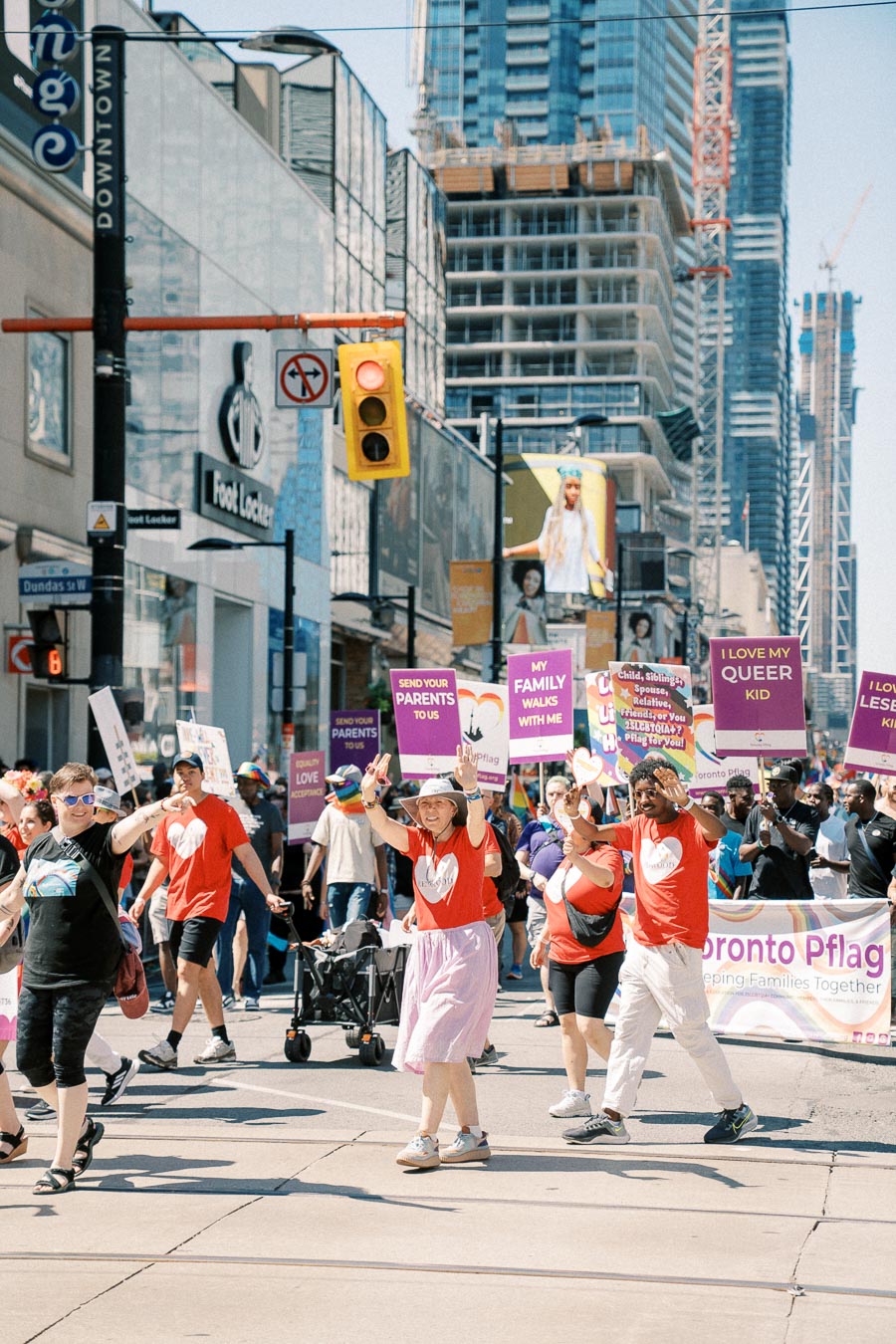Participants in a Toronto pride parade march with supportive signs for LGBTQ+ rights, showcasing community solidarity.