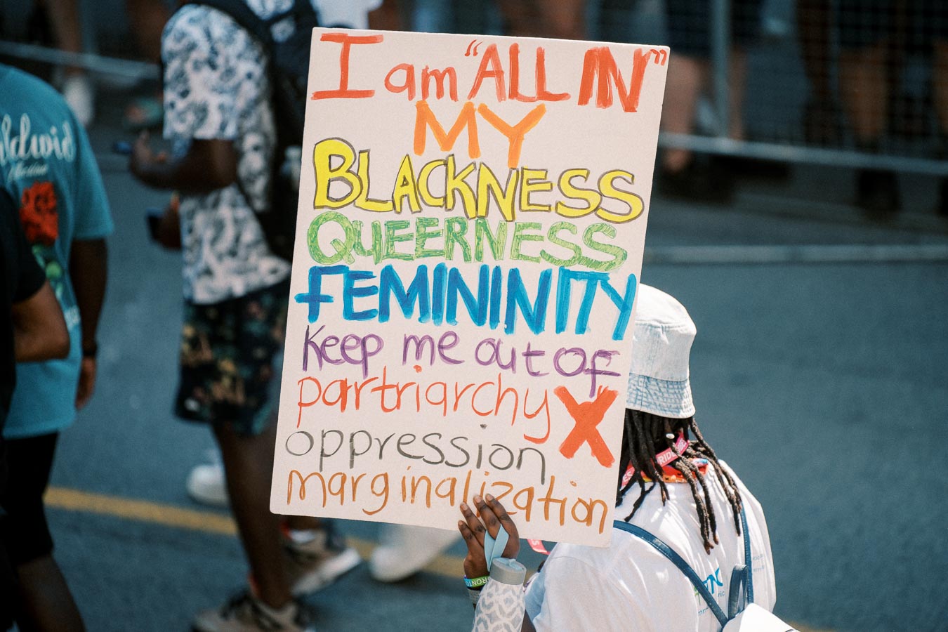 A protester holds a sign advocating for blackness, queerness, and femininity, while rejecting patriarchy, oppression, and marginalization.