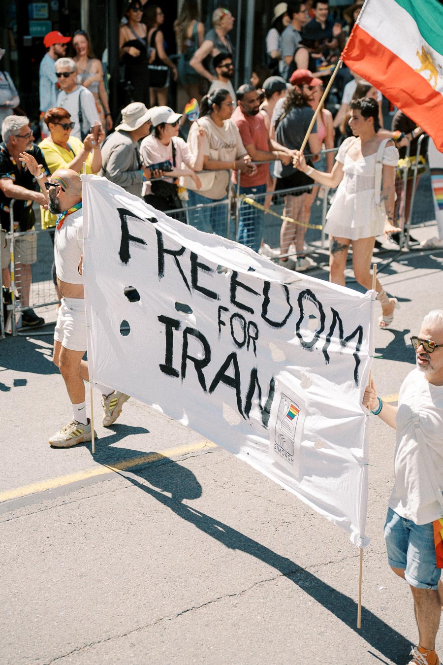 Participants in a parade hold a banner reading 'Freedom for Iran', advocating for freedom and human rights.