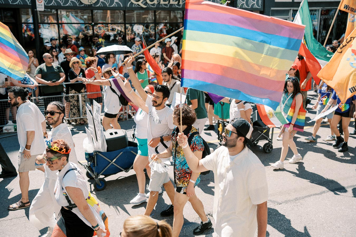 Participants in a pride parade march with rainbow flags and vibrant attire, celebrating diversity and inclusion.