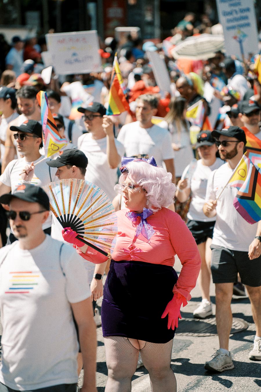 Participants celebrate diversity at a lively parade, showcasing rainbow flags and colorful attire.