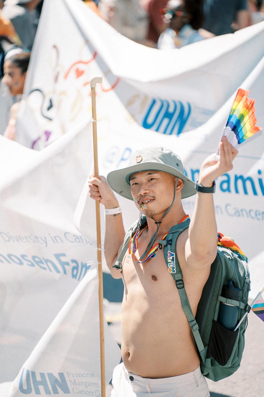 A participant in a pride parade holds a rainbow fan and a banner, celebrating diversity and inclusion.