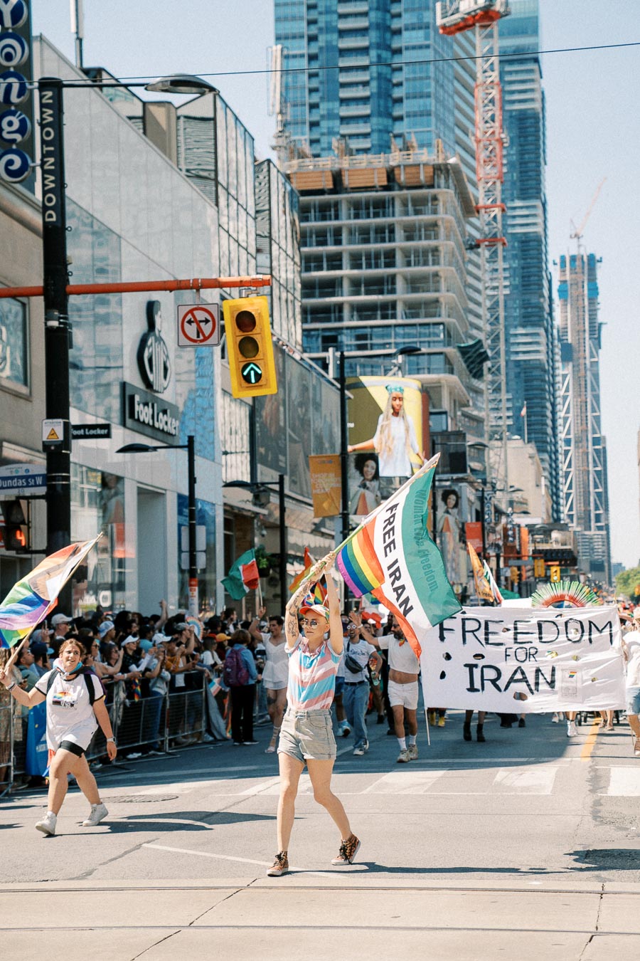 Protesters march in downtown Toronto, holding 'Free Iran' banners and flags, advocating for freedom and human rights.