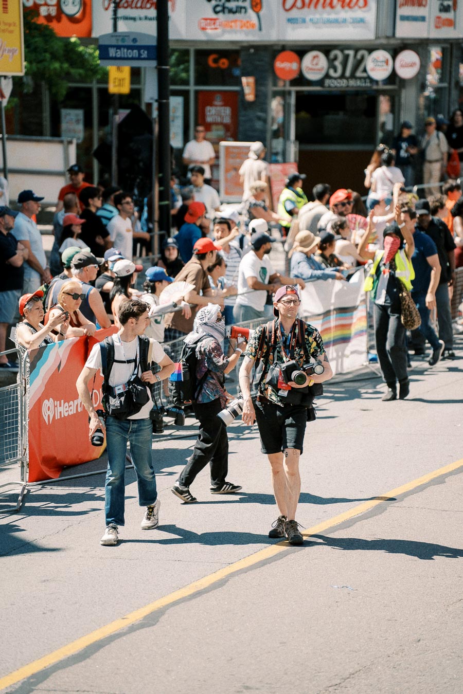 Photographers and a crowd gather on a city street during a public event, with various people capturing the moment.