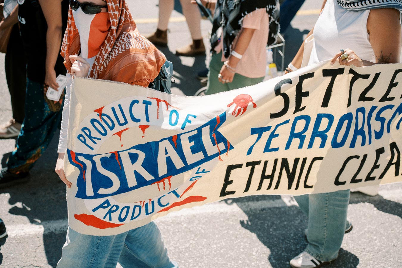 Protesters hold a banner with anti-Israel messages during a demonstration, highlighting political tensions.