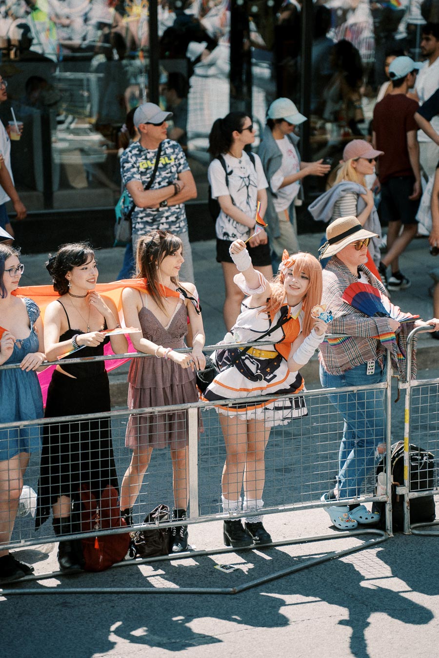 A lively scene at a parade with participants dressed in colorful outfits, including a person in cosplay holding a rainbow flag, celebrating diversity and inclusion.
