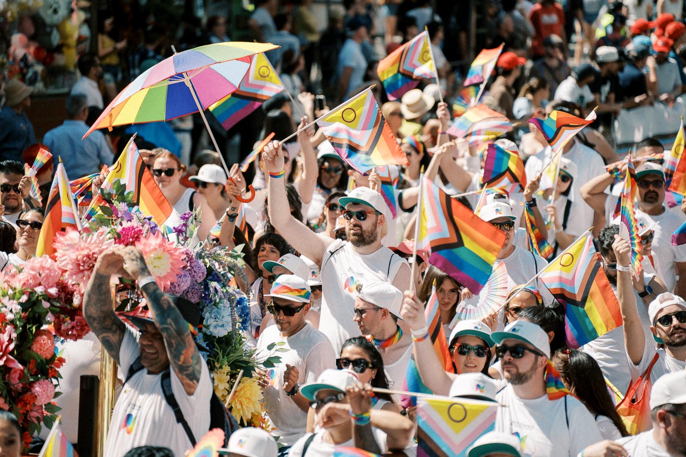A vibrant scene from a Pride parade with participants waving rainbow flags and wearing themed attire, celebrating diversity and inclusion.