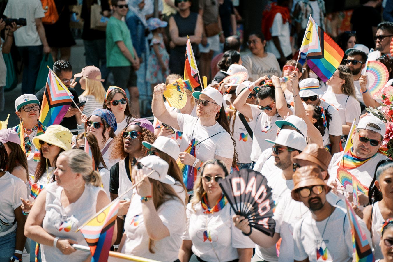Participants at a Pride parade celebrate diversity and inclusion with rainbow flags and vibrant attire.