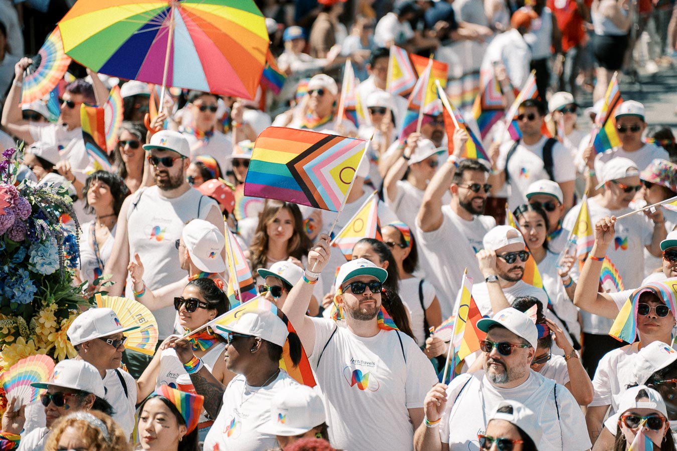 Participants in a Pride parade celebrate with rainbow flags and colorful attire, showcasing support for the LGBTQ+ community.