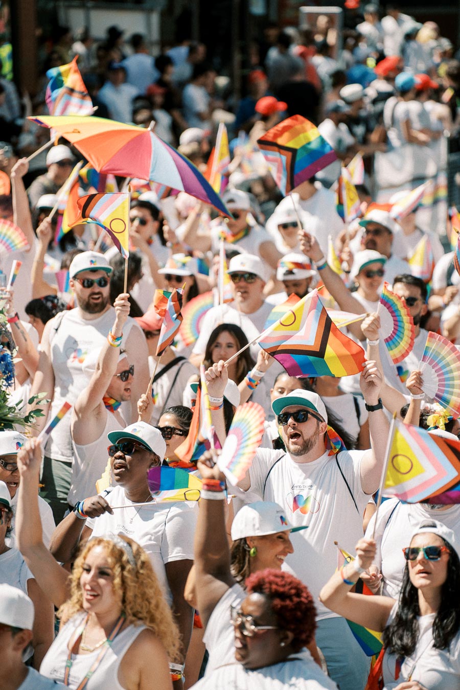 A vibrant scene from a Pride parade, featuring a diverse crowd celebrating with rainbow flags and colorful attire.