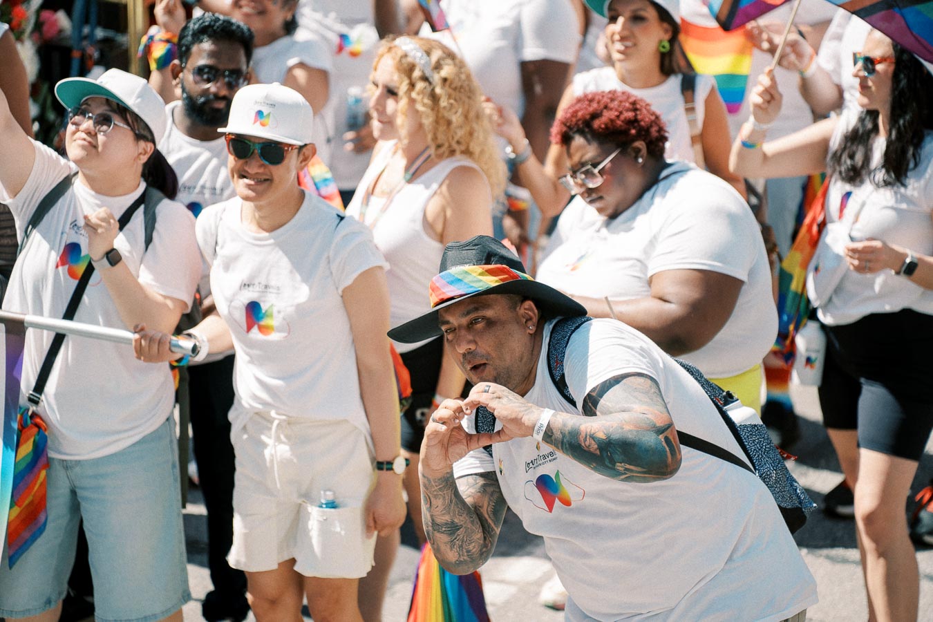 Participants at a pride parade wearing white shirts with rainbow designs, celebrating diversity and inclusion.