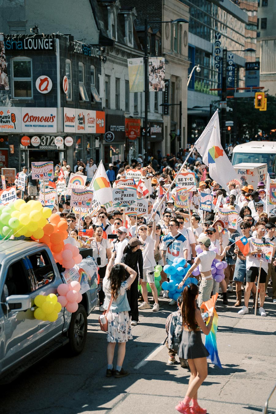 Participants celebrate diversity and inclusion at a lively pride parade, holding rainbow flags and signs advocating for LGBTQ+ rights.