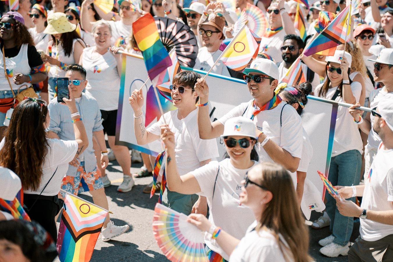 Participants at a pride parade celebrate with rainbow flags and vibrant attire, showcasing support for the LGBTQ+ community.