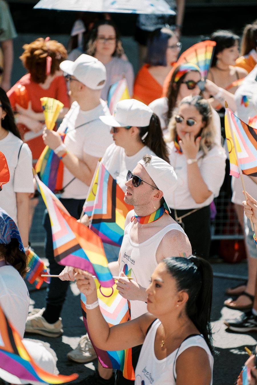 Participants at a pride parade celebrate with rainbow flags and colorful attire, showcasing support for the LGBTQ+ community.