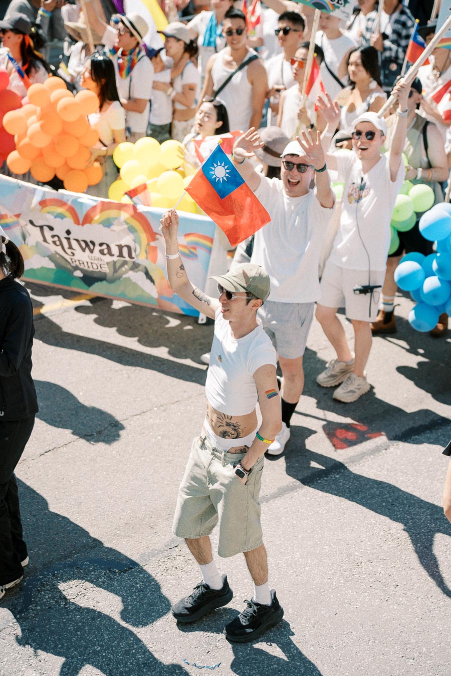 Participants in a pride parade celebrate with a Taiwanese flag and vibrant balloons, showcasing support for Taiwan Pride.