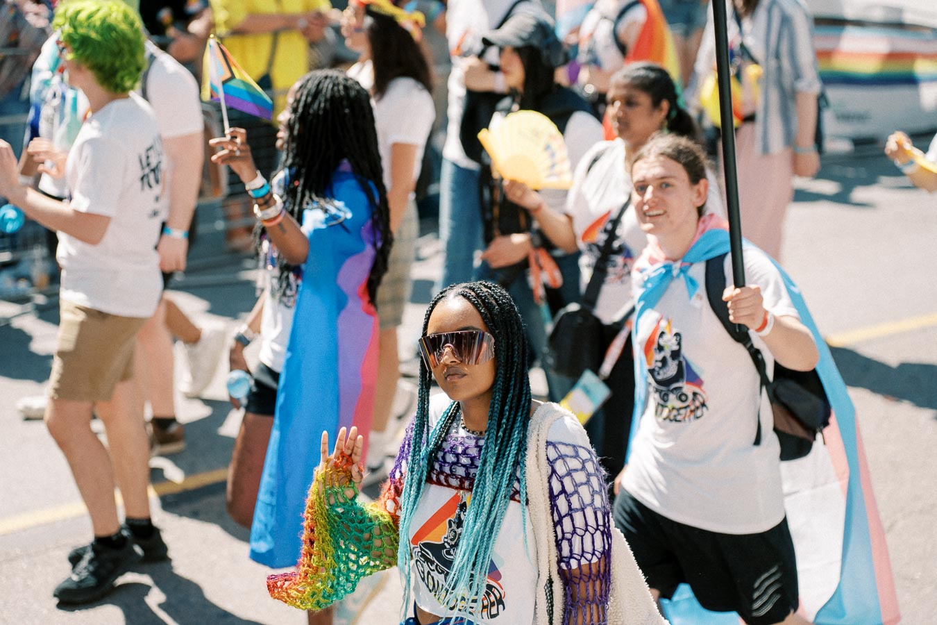 Participants in a pride parade celebrate with colorful attire and flags, showcasing diversity and inclusion.