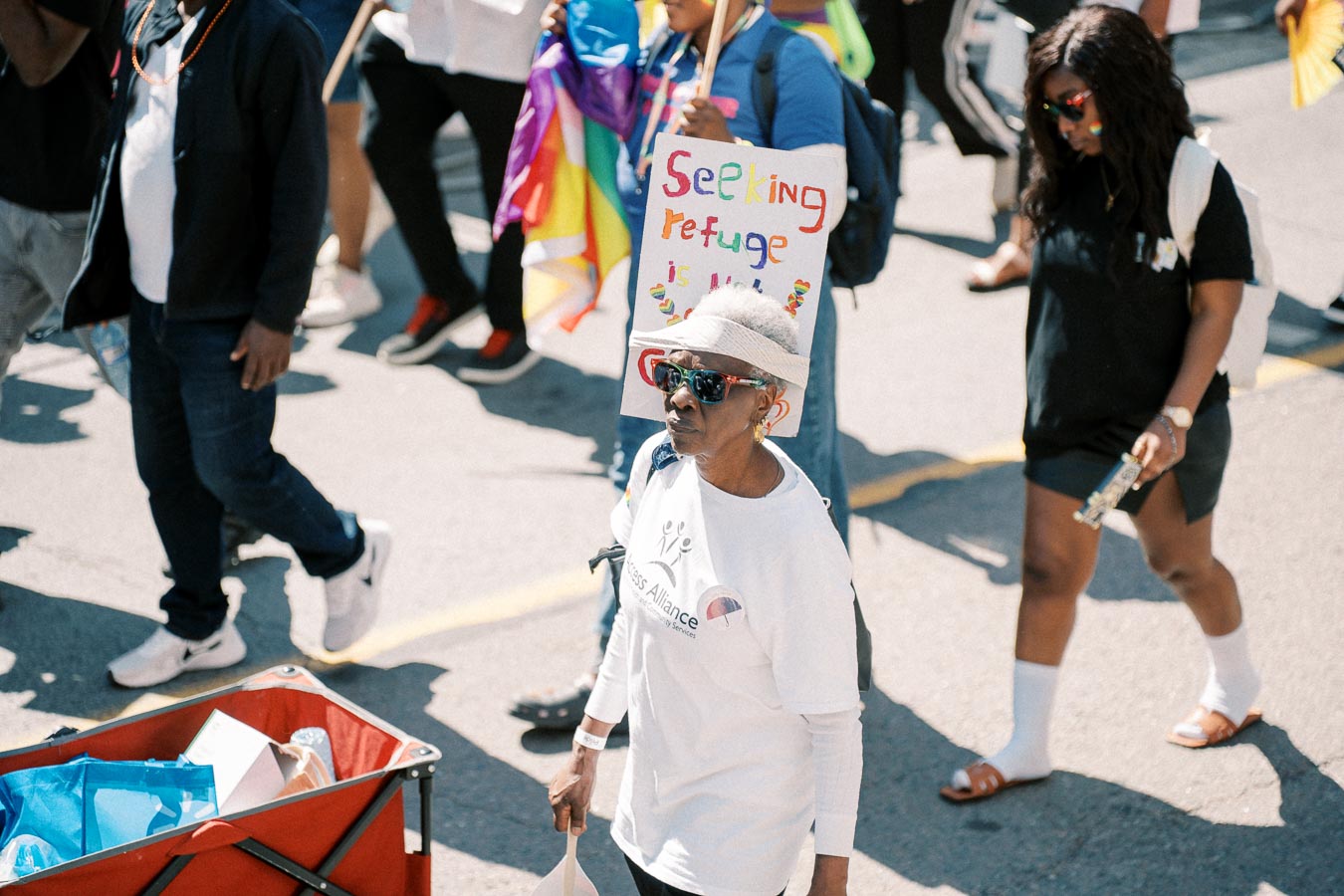 Participants in a march advocating for refugee rights, with a prominent sign reading 'Seeking refuge is not a crime'.