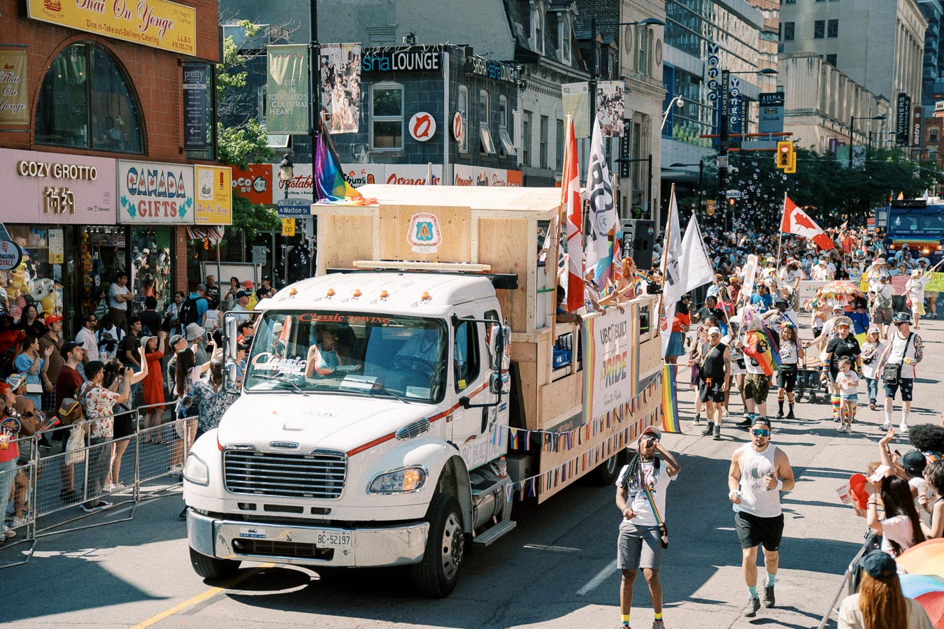 A vibrant parade in Toronto with a truck float and participants celebrating with flags and banners.