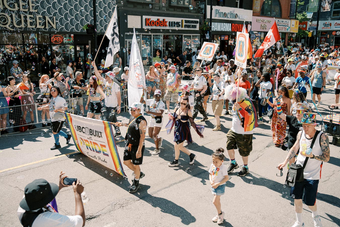 Participants march in a lively Pride parade, celebrating diversity and inclusion with colorful flags and banners.