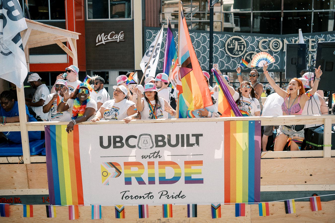 Participants on a float at the Toronto Pride Parade celebrate with rainbow flags and vibrant attire, showcasing support for the LGBTQ+ community.