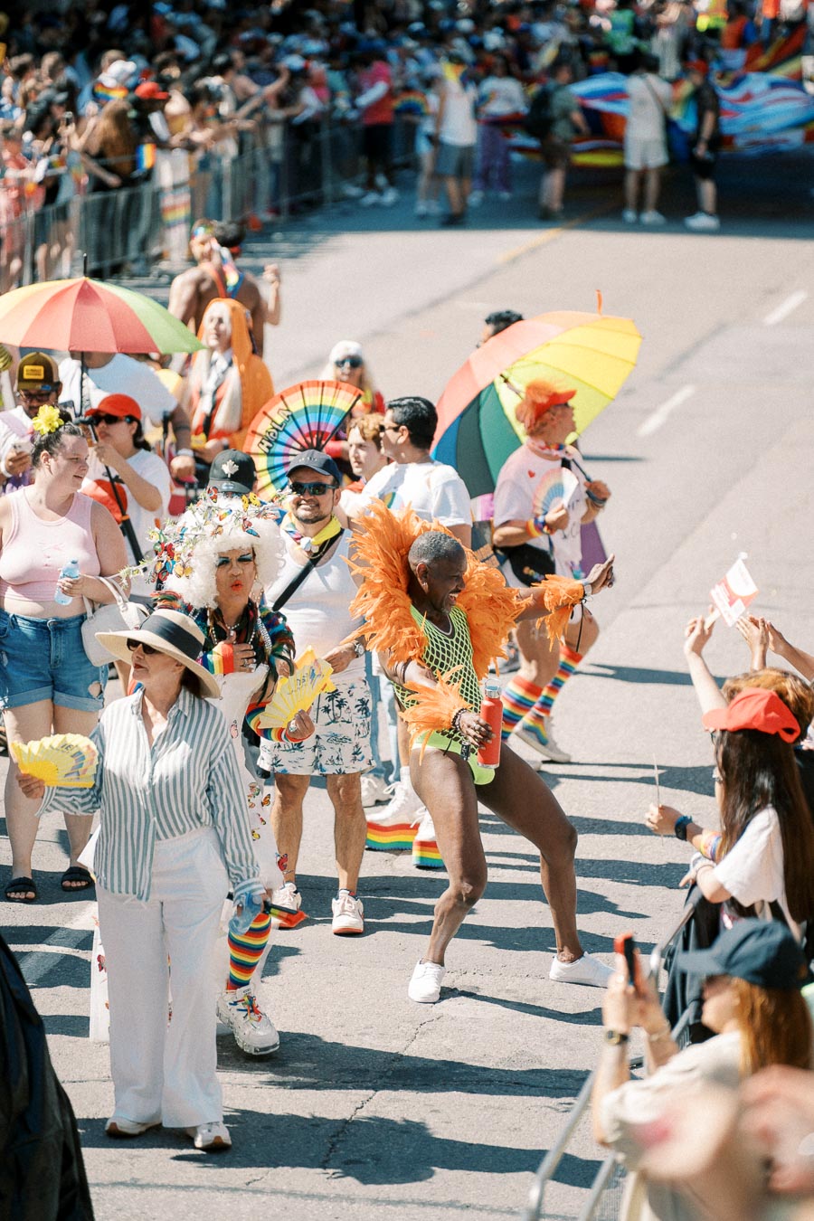 Participants in colorful outfits and rainbow accessories celebrate at a lively parade.