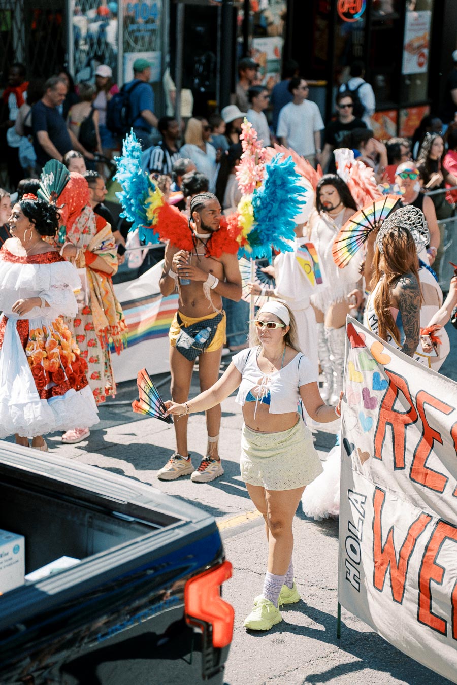 Participants in colorful costumes and rainbow accessories take part in a lively street parade, celebrating diversity and inclusion.