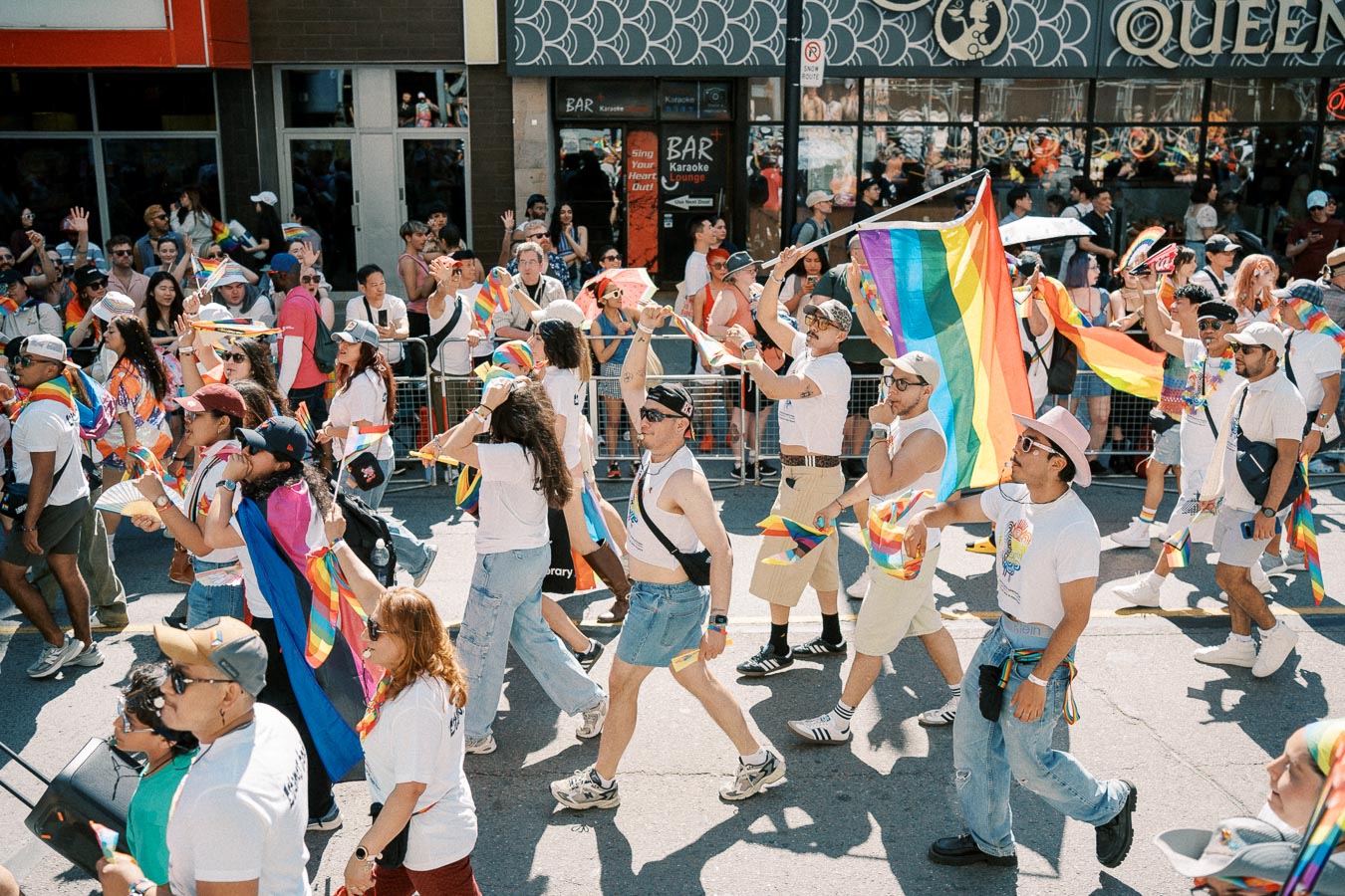 Participants march in a vibrant pride parade, celebrating diversity and inclusion with rainbow flags and festive attire.