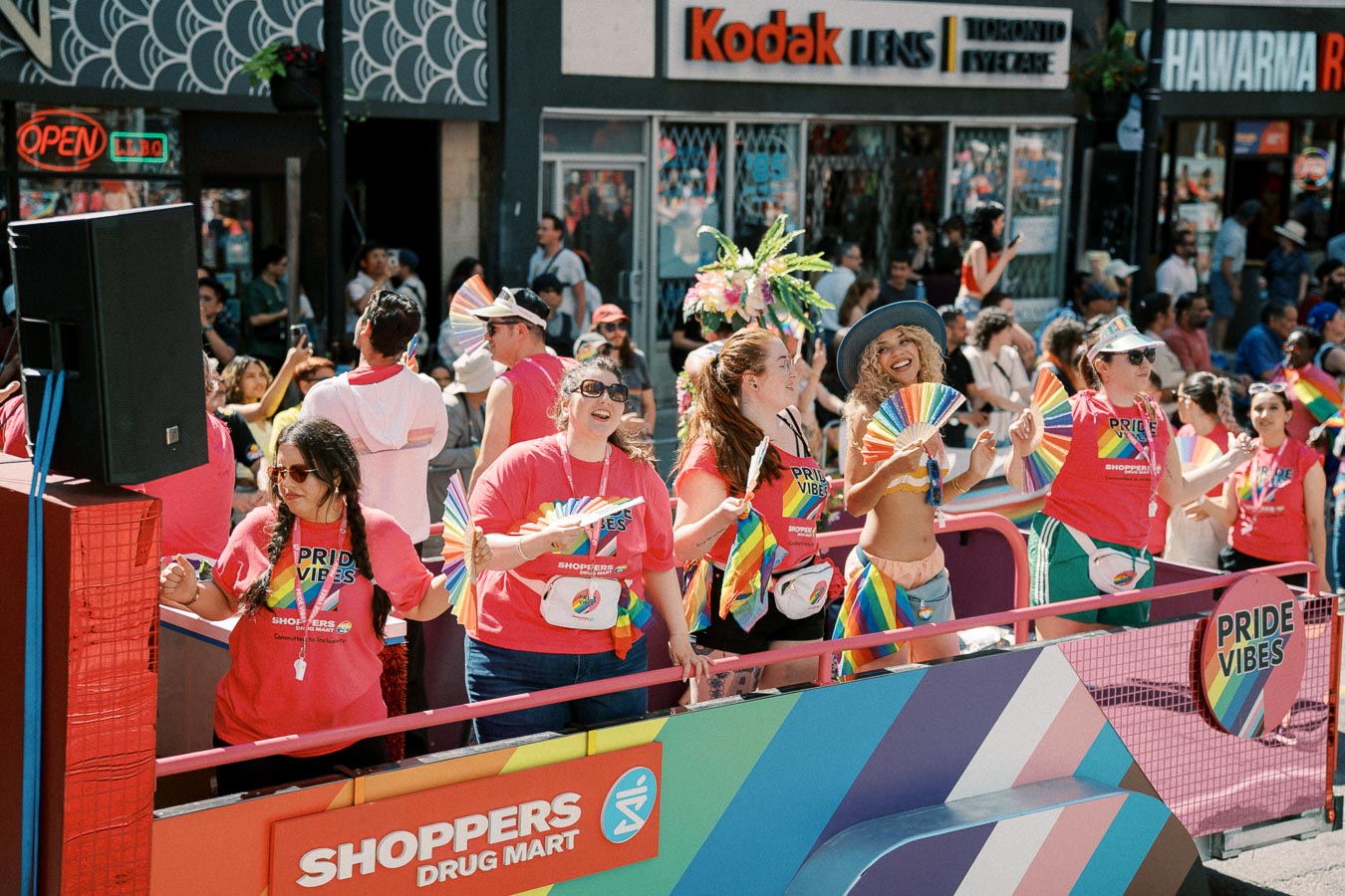 Participants at a Pride parade wearing 'Pride Vibes' shirts and holding rainbow fans, celebrating diversity and inclusion.