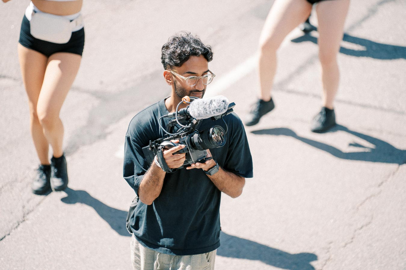 A videographer captures footage on a busy street, surrounded by people.