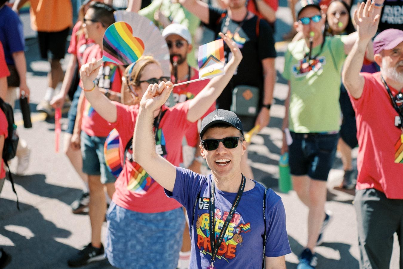 Participants at a pride parade celebrate with rainbow flags and vibrant attire, showcasing support for the LGBTQ+ community.