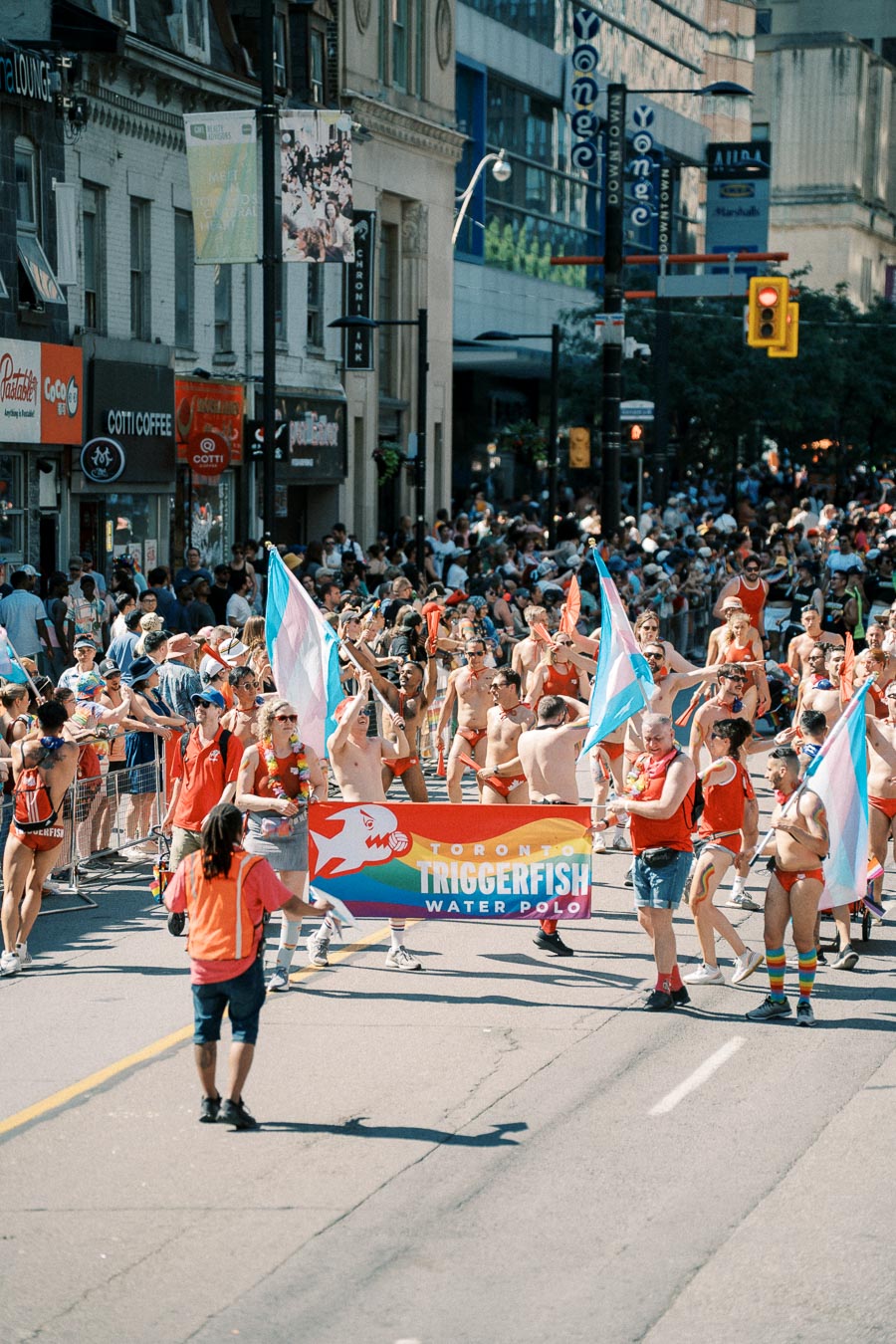 Participants in a pride parade march with a banner for Toronto Triggerfish Water Polo, celebrating diversity and inclusion.