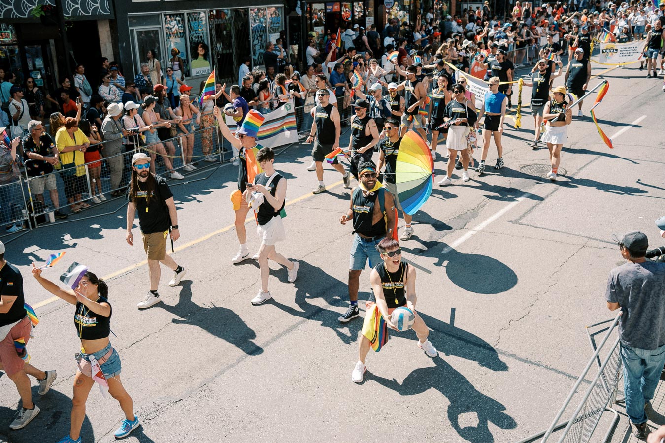 Participants in a vibrant parade wave rainbow flags and carry colorful umbrellas, celebrating diversity and inclusion.