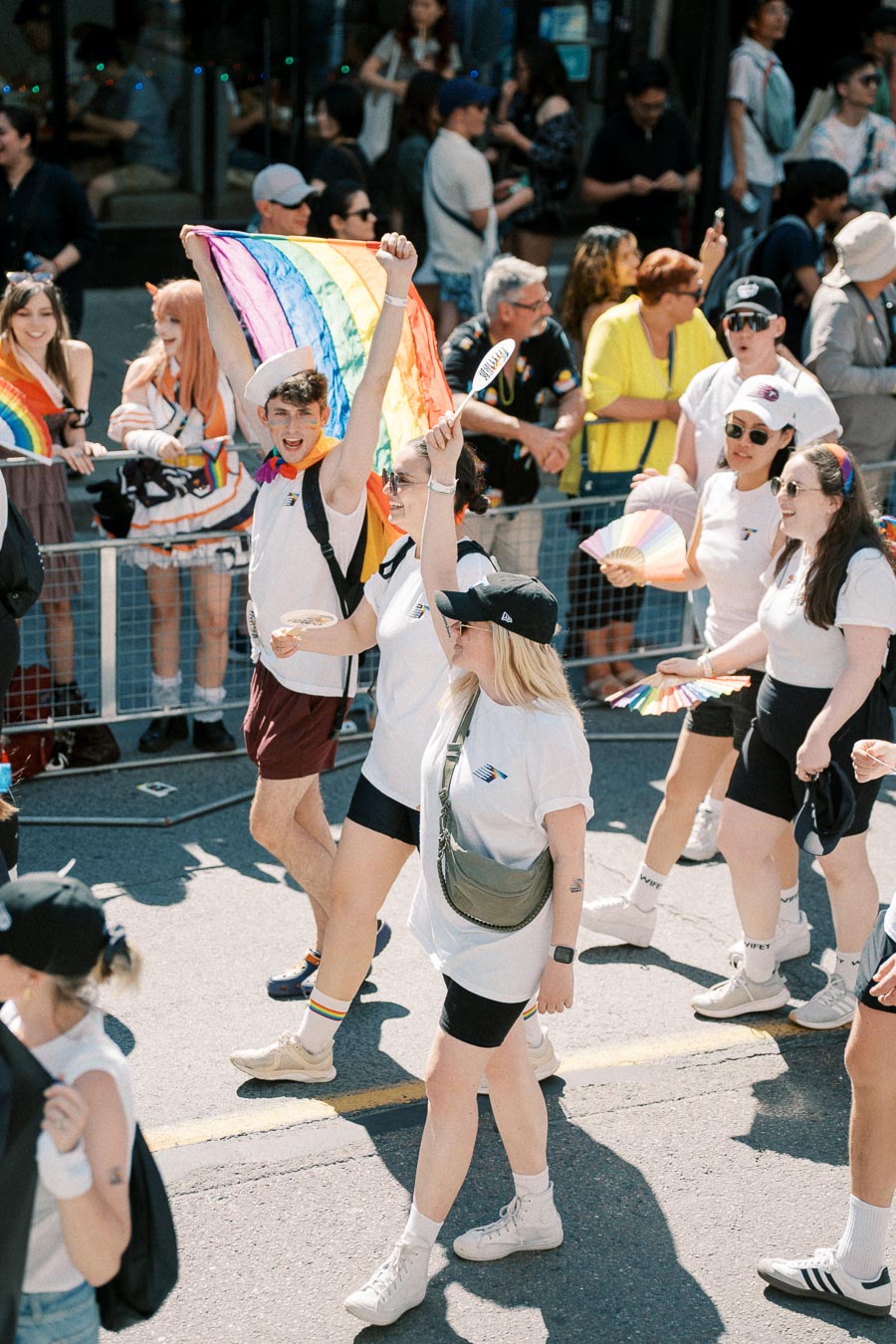 Participants in a pride parade celebrate with rainbow flags and colorful attire, showcasing support for the LGBTQ+ community.