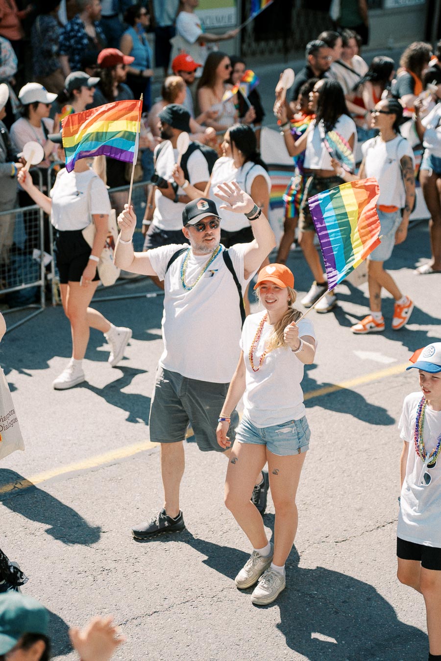 Participants in a pride parade wave rainbow flags and wear colorful accessories, celebrating diversity and inclusion.